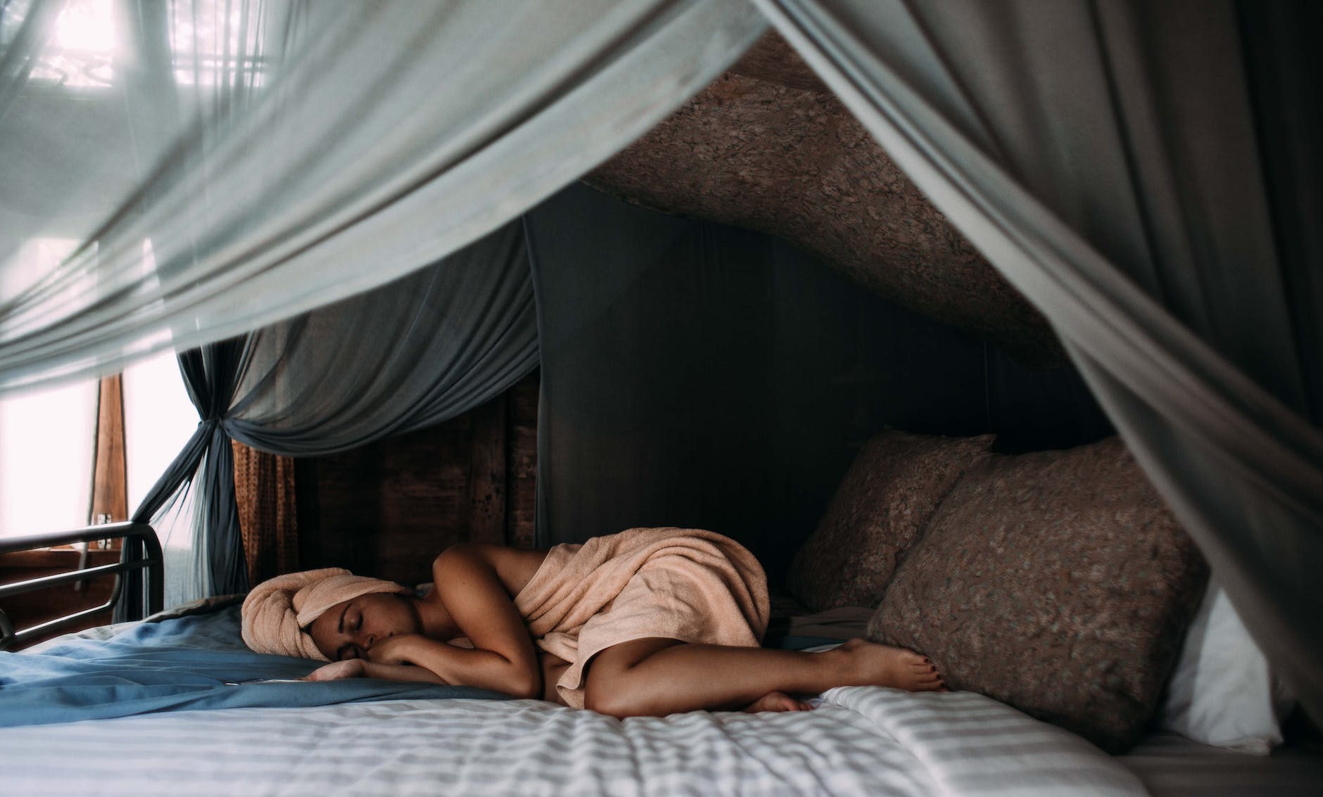 woman lying on bed wrapped around a towel